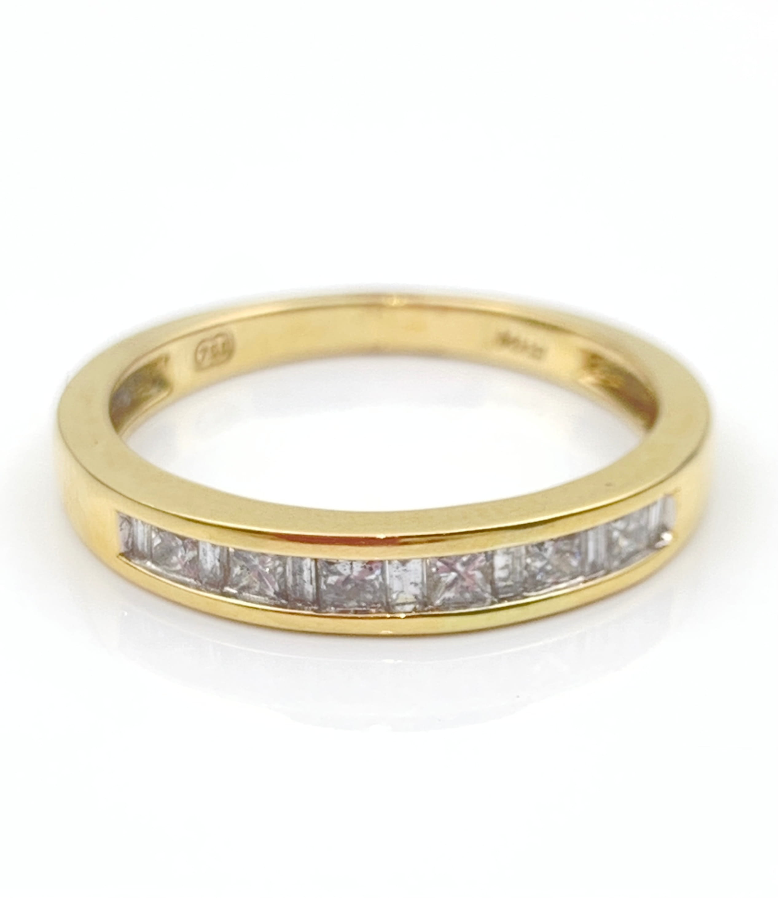 Gold ring with a row of diamonds set in a gold band, photographed from above on white background