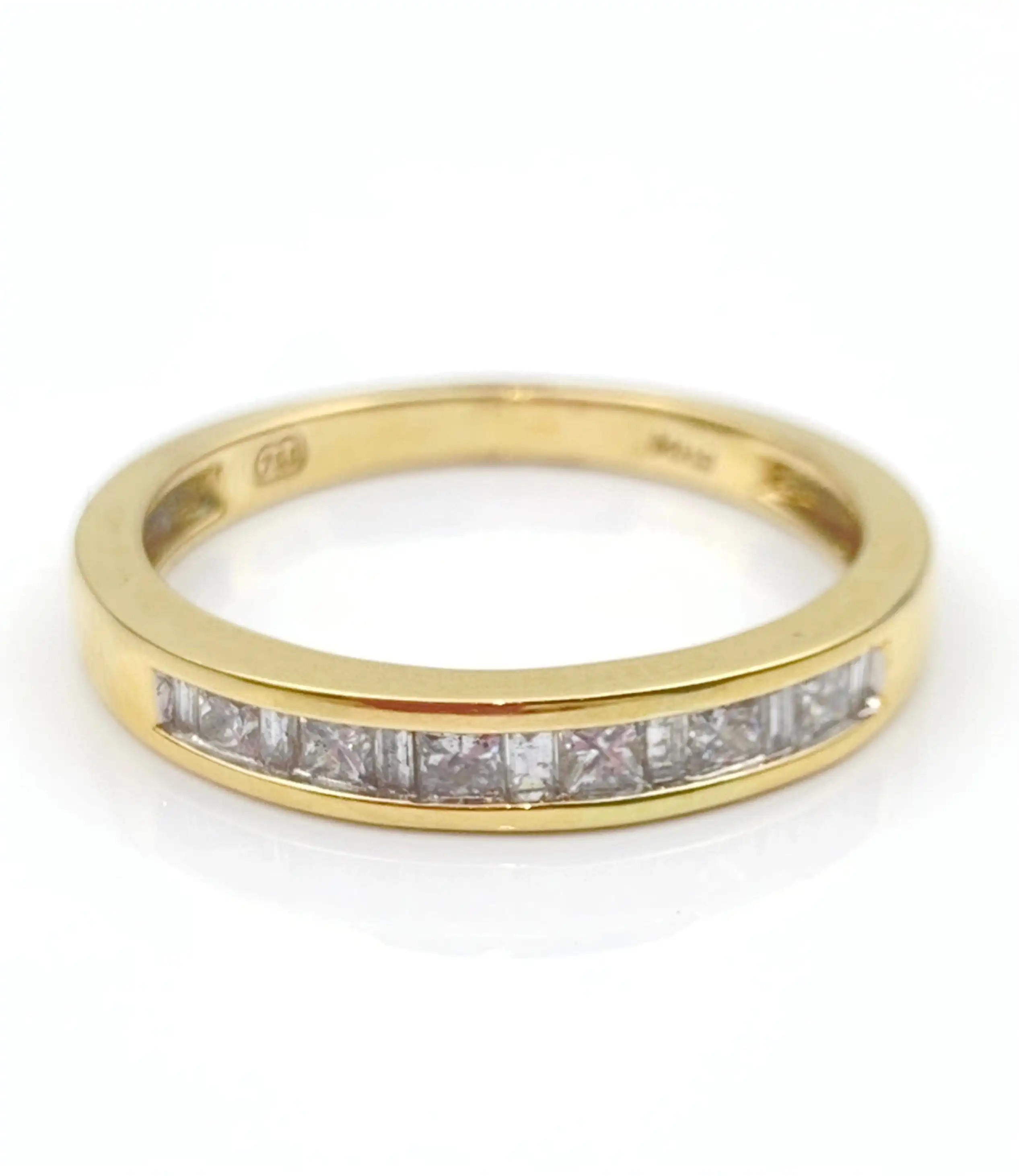 Gold ring with a row of diamonds set in a gold band, photographed from above on white background