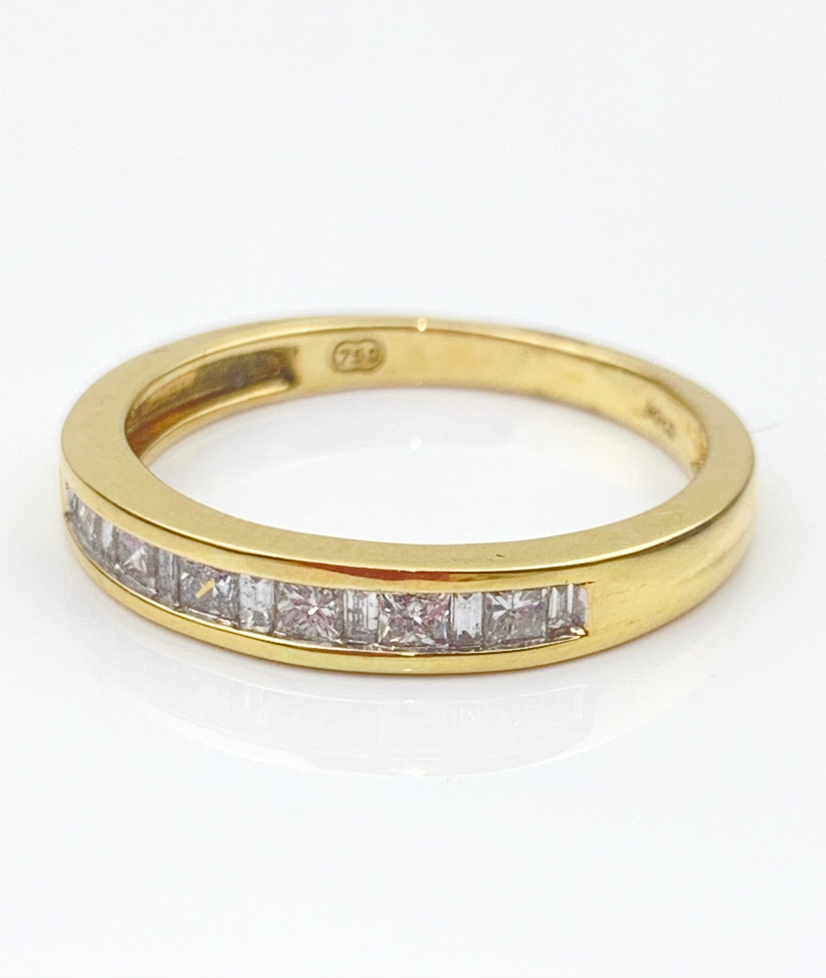 Gold ring with a row of square-cut diamonds around the band on a white background (inner hallmark visible).