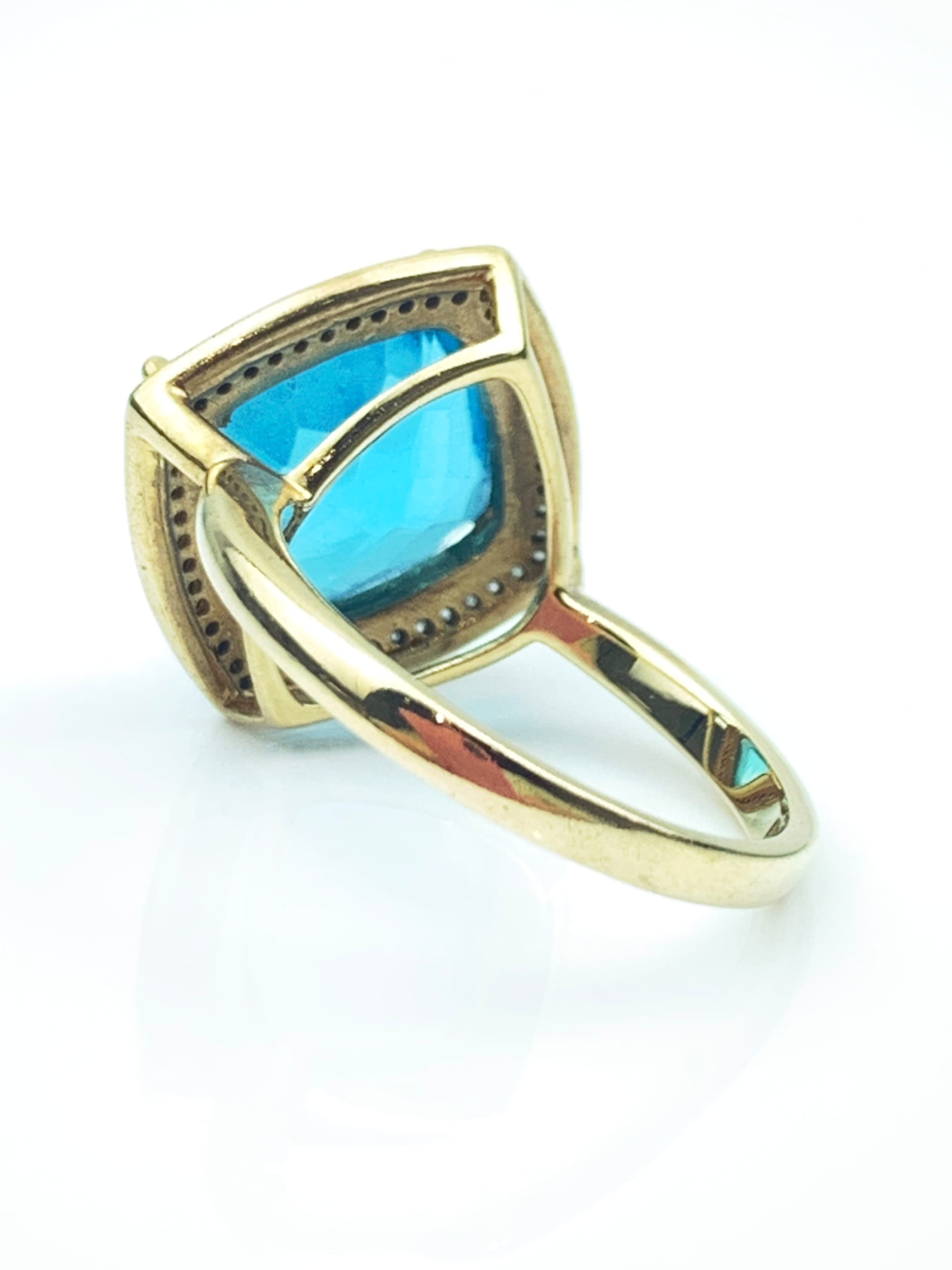 Close-up of a gold ring with a large blue rectangular gemstone set in a beaded bezel.