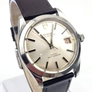 Close-up of a Tudor wristwatch with a silver dial, black hour markers, and a black leather strap.
