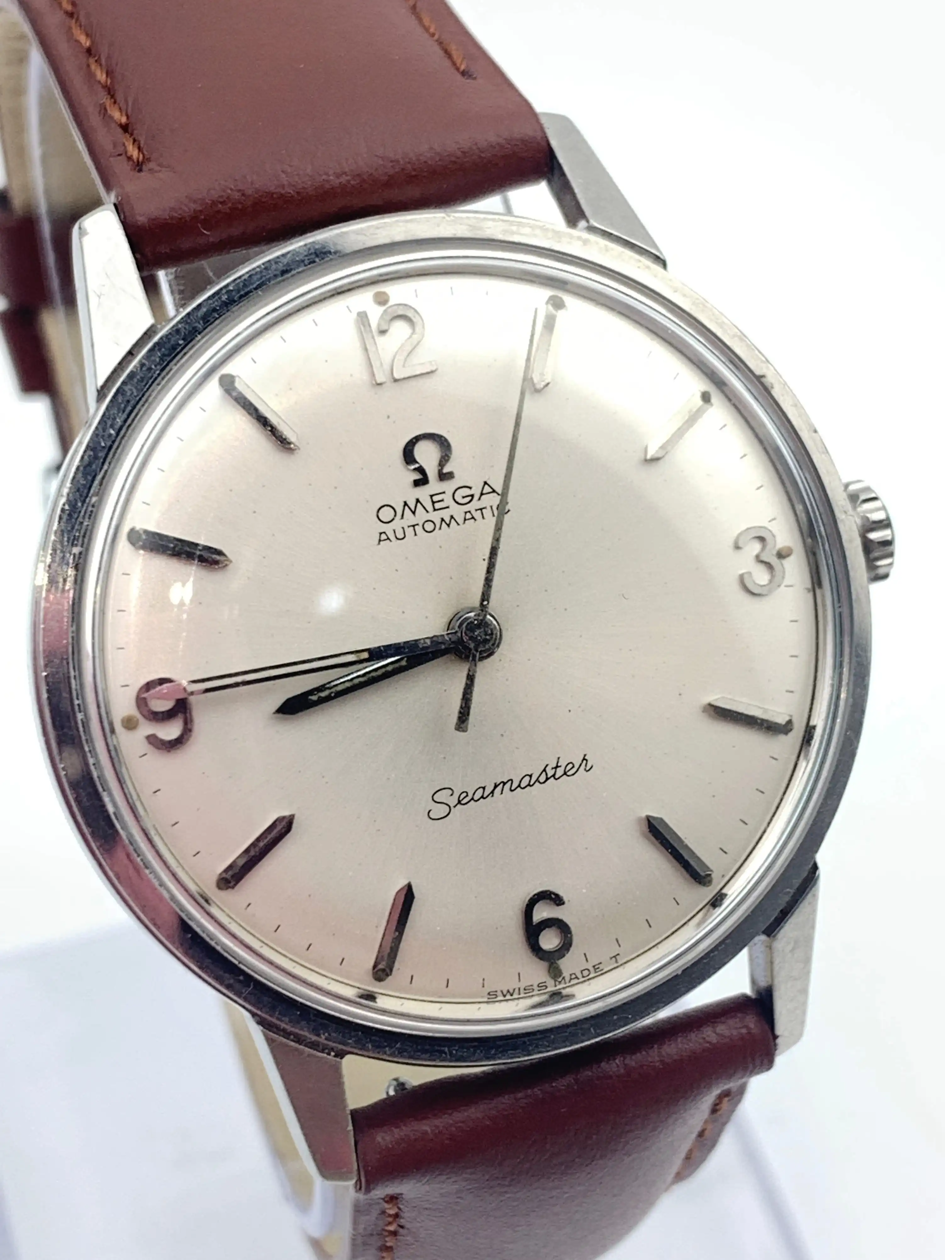 Omega Seamaster automatic wristwatch with a silver dial and brown leather strap (close-up).